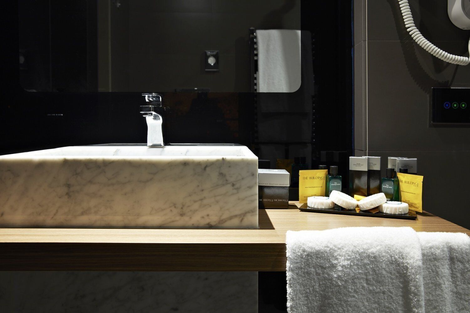 A bathroom with a marble sink, toiletries, and a towel rack.