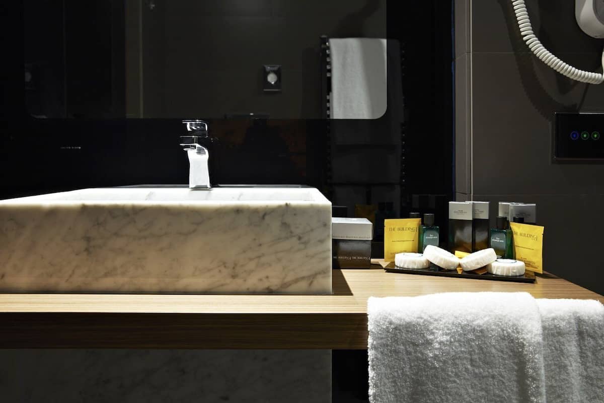A bathroom with a marble sink, toiletries, and a towel rack.