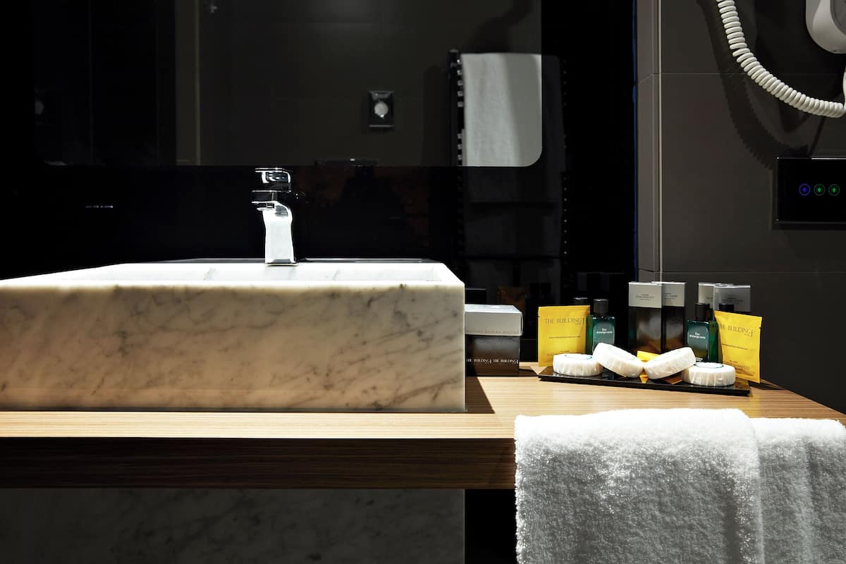 A marble sink with a modern faucet, a wooden countertop, and toiletries including a toothbrush, toothpaste, and a towel.