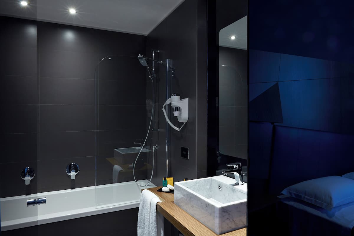 A modern bathroom with a glass-enclosed shower, a large white sink, and a wooden countertop.