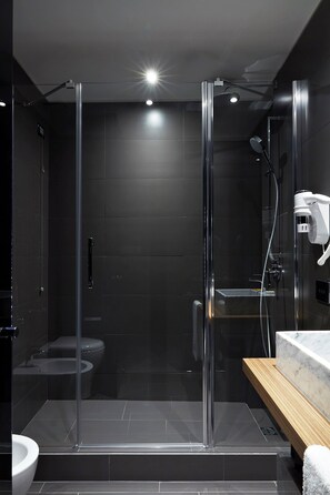 A modern bathroom with a glass-enclosed shower, a wooden vanity, and a marble countertop. - The Building (Rome)