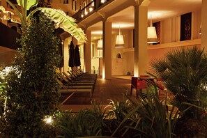 Un'accogliente hall d'albergo con una lunga reception, diverse zone relax e una scala che conduce a un piano superiore.
