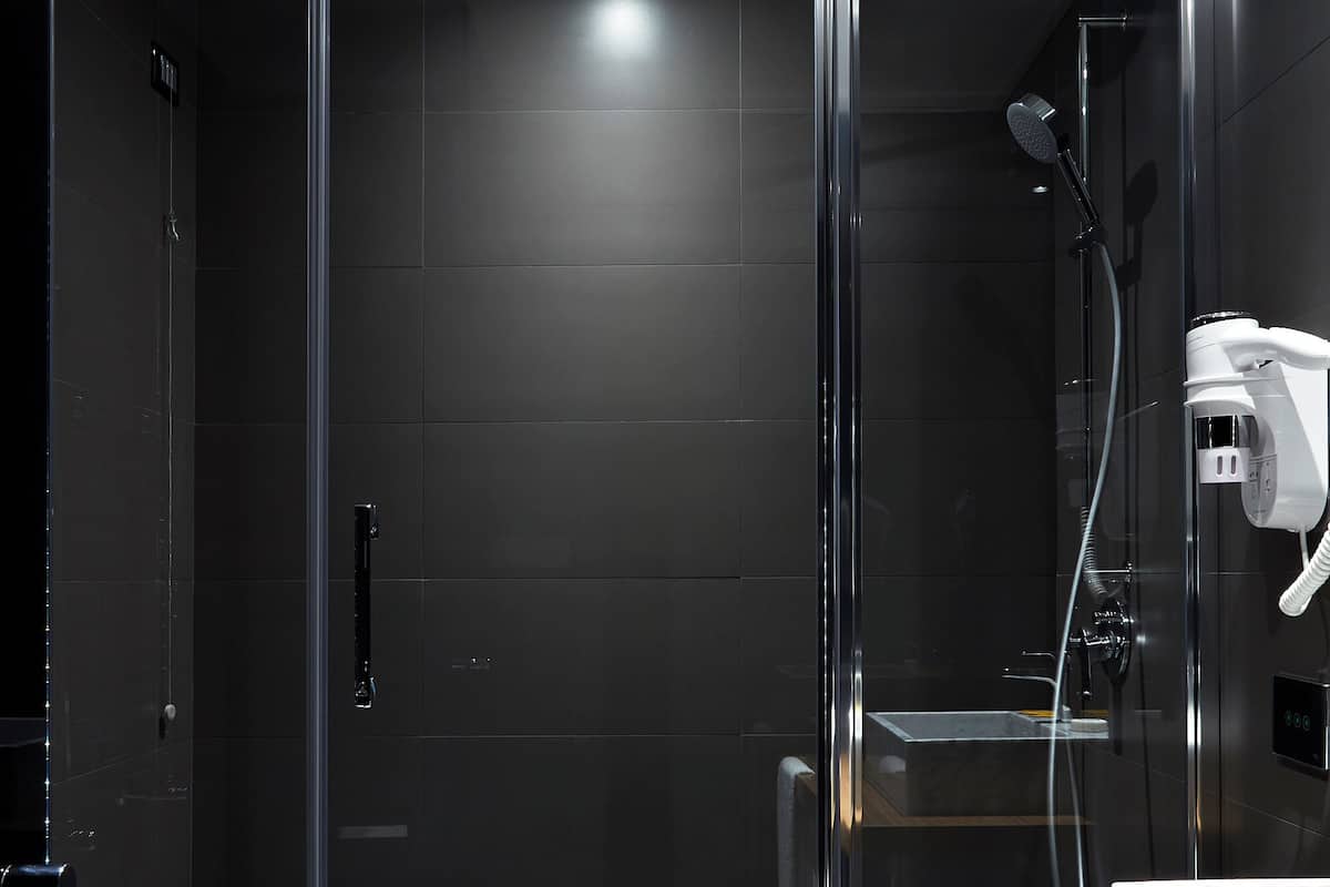A modern bathroom with a glass-enclosed shower, a wooden vanity, and a marble sink.