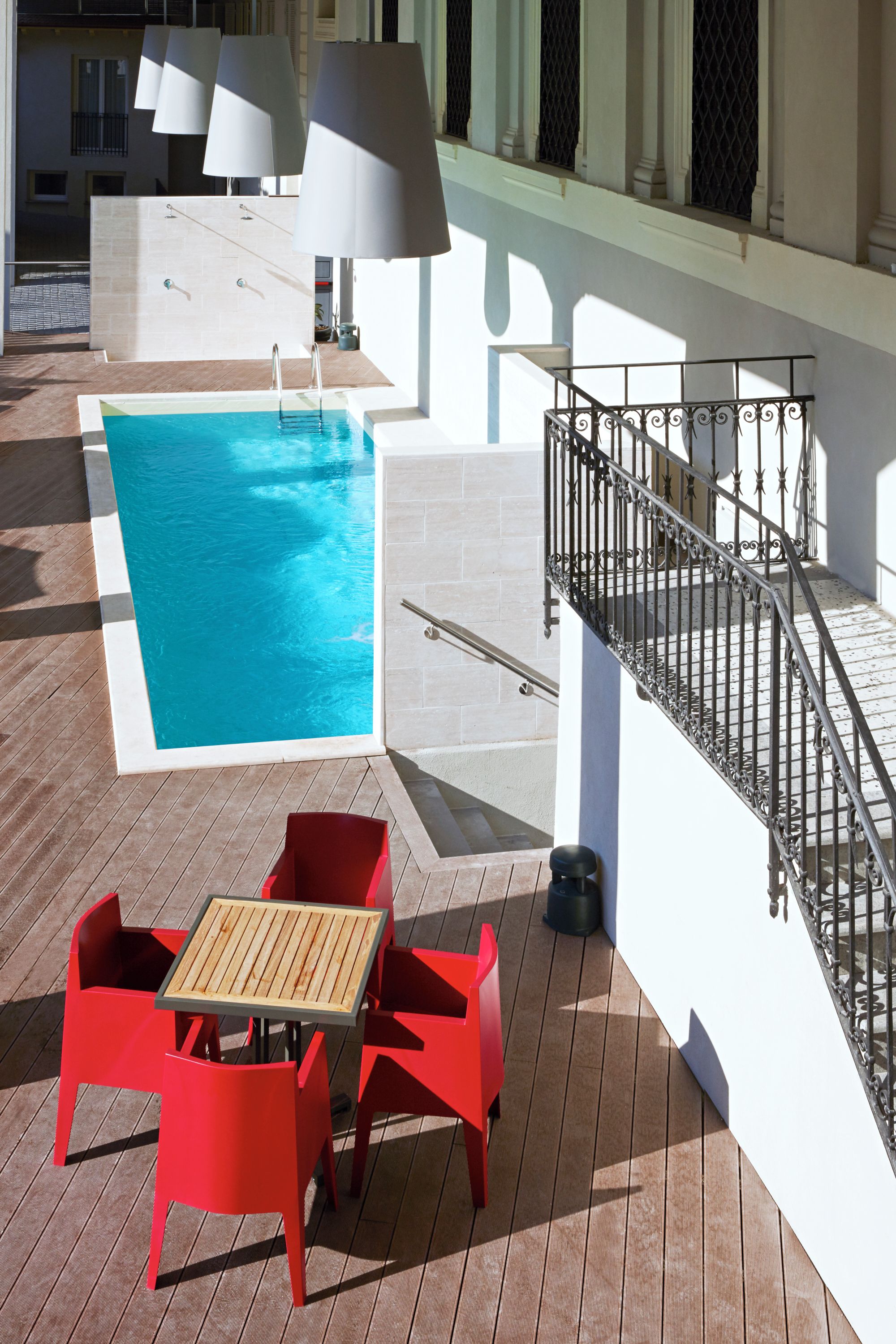 A pool area with a table and chairs, a staircase, and outdoor lighting.