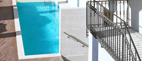 A pool area with a table and chairs, a staircase, and outdoor lighting.