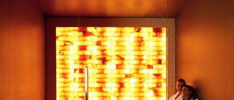 A modern sauna room with wooden benches and a large, illuminated wall.