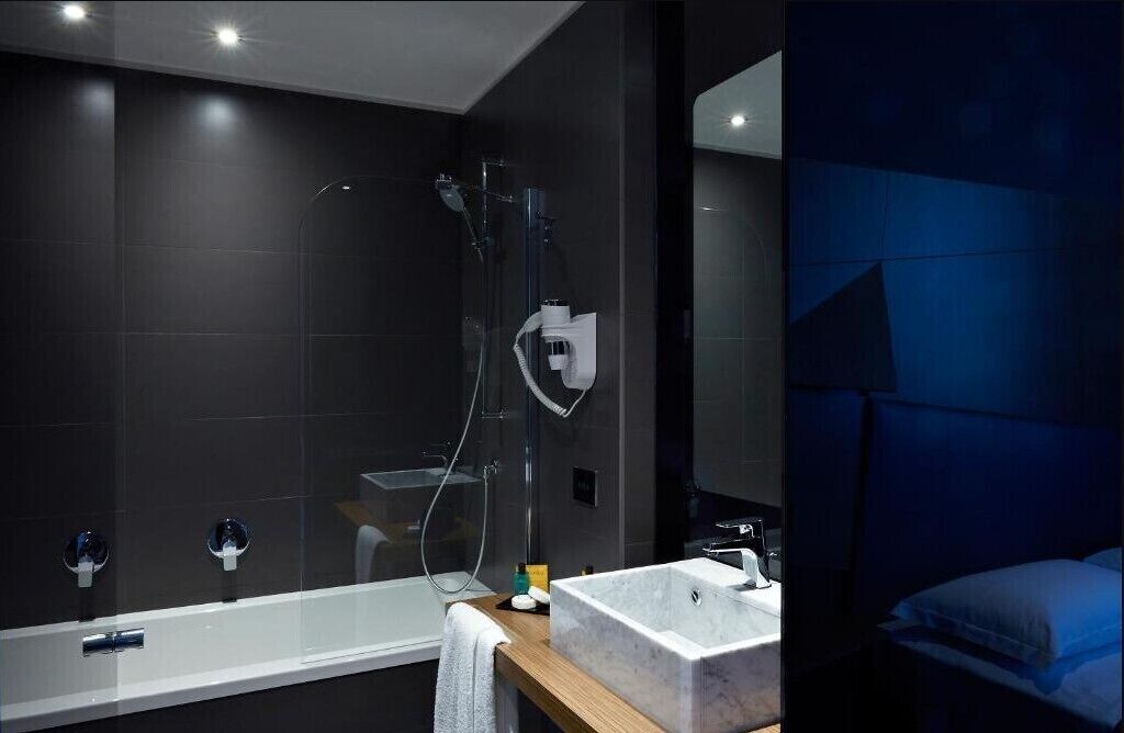 A modern bathroom with a glass-enclosed shower, a standalone bathtub, and a large mirror.