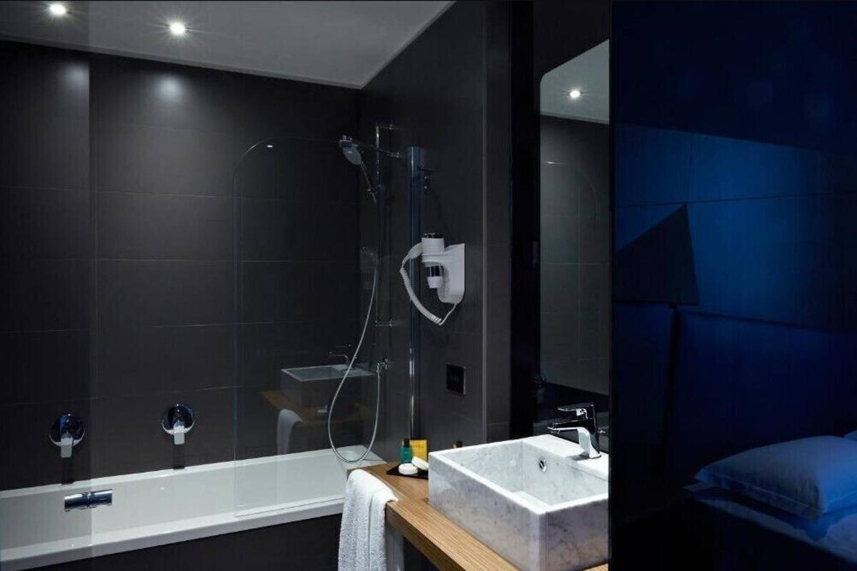 A modern bathroom with a glass-enclosed shower, a standalone bathtub, and a vanity with a sink.