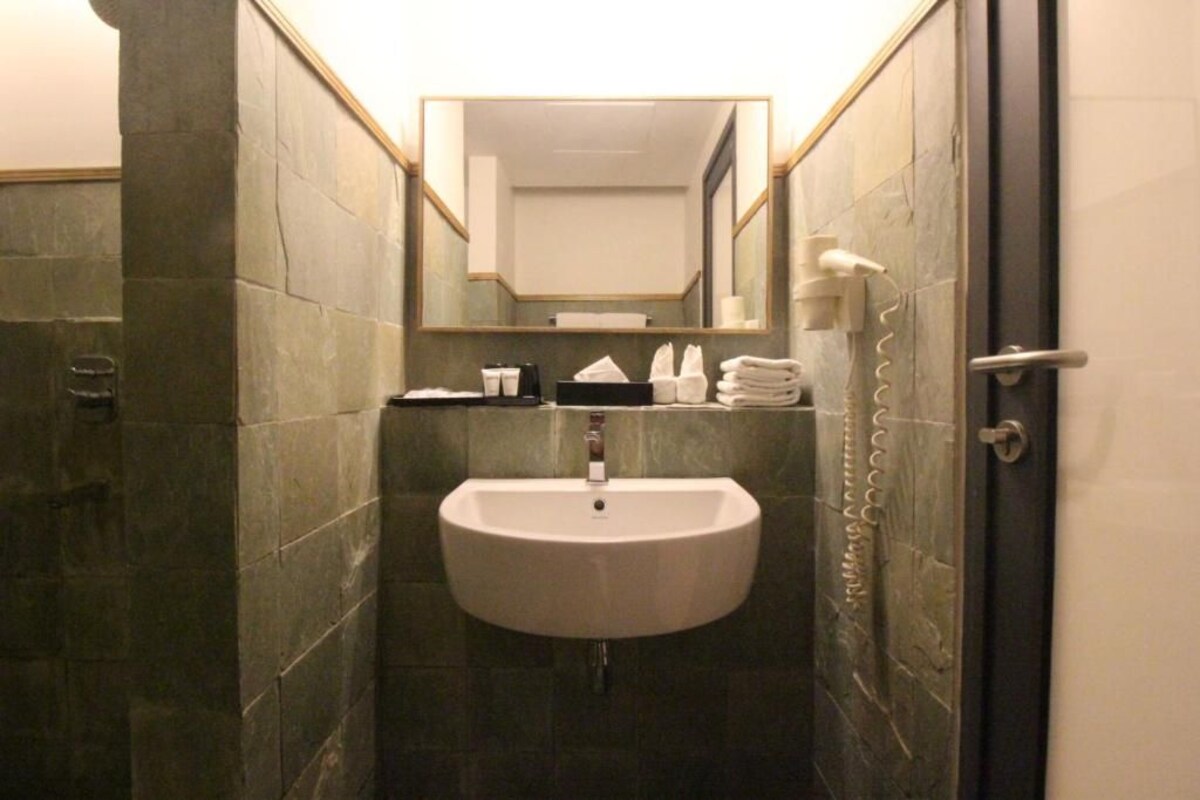 A bathroom with a white sink, a mirror, and a towel rack.