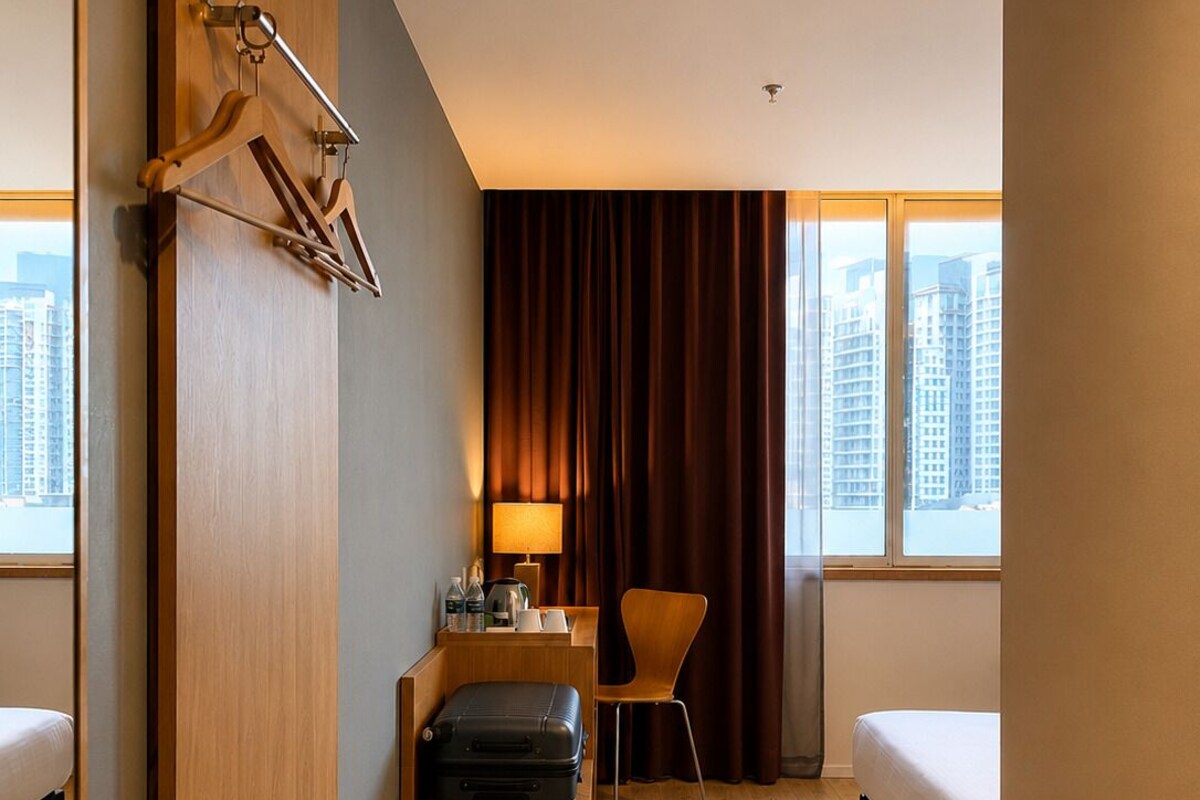 Une chambre d’hôtel avec un lit, un bureau doté d’une lampe, une chaise et une valise.