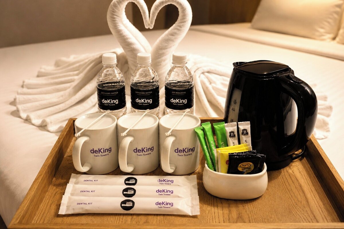 Un plateau contenant des articles de la marque deKing Twin Towers, notamment des bouteilles d’eau, des tasses, des kits de soins dentaires et une machine à café.