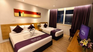 Une chambre d’hôtel avec deux lits, une télévision, un bureau et une fenêtre avec des rideaux.