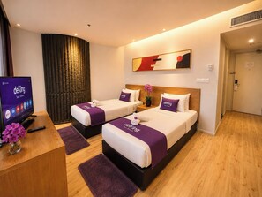 Une chambre d’hôtel avec deux lits, une télévision et un bureau agrémenté d’un vase de fleurs.