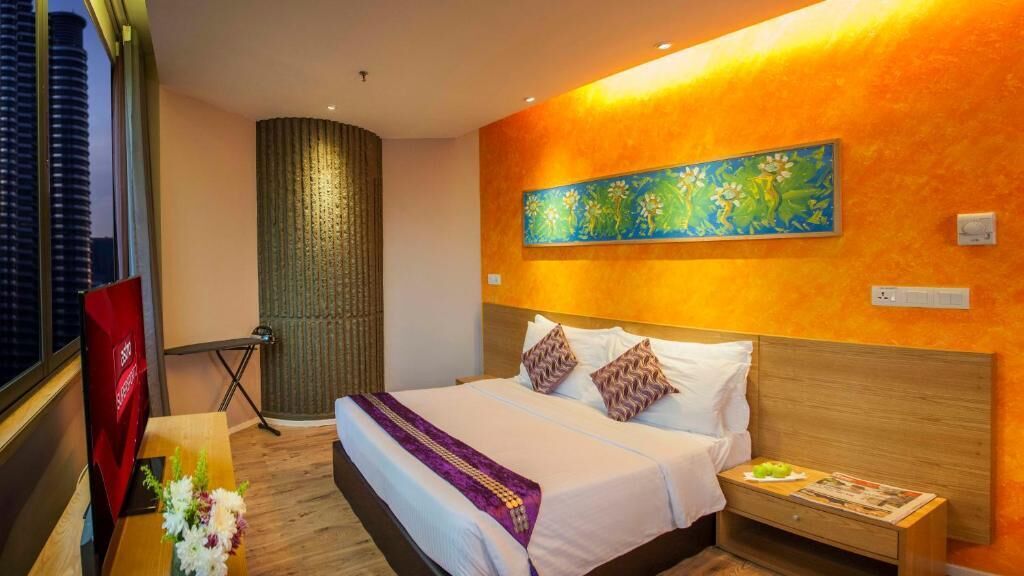 Een hotelkamer met een groot bed, een schilderij aan de muur, een nachtkastje en uitzicht op een gebouw.