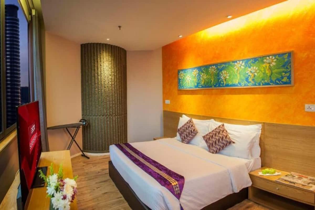 Ein Hotelzimmer mit einem großen Bett, einem Bild an der Wand, einem Nachttisch und Blick auf ein Gebäude.