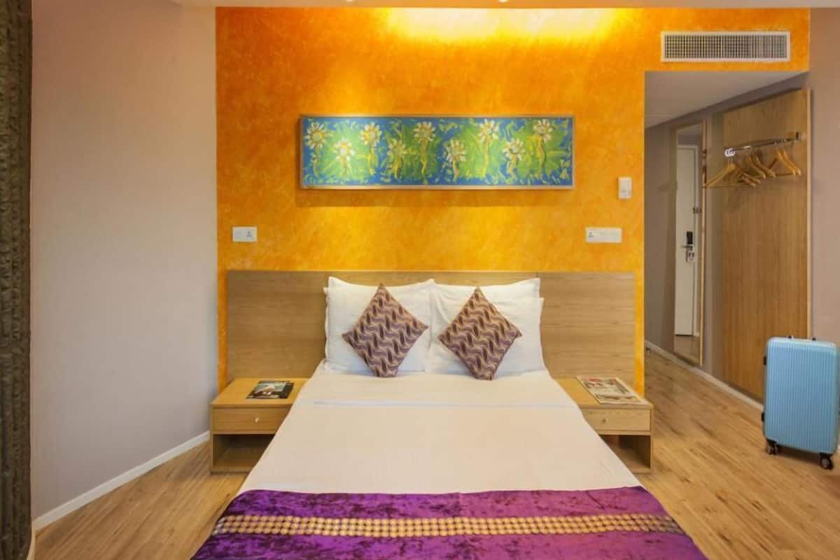 Ein Hotelzimmer mit einem großen Bett, einem Holzkopfende, zwei Nachttischen, einem Wandbild und einem Koffer.