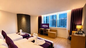 Une chambre d’hôtel avec deux lits, une télévision, un bureau et une vue sur la ville.