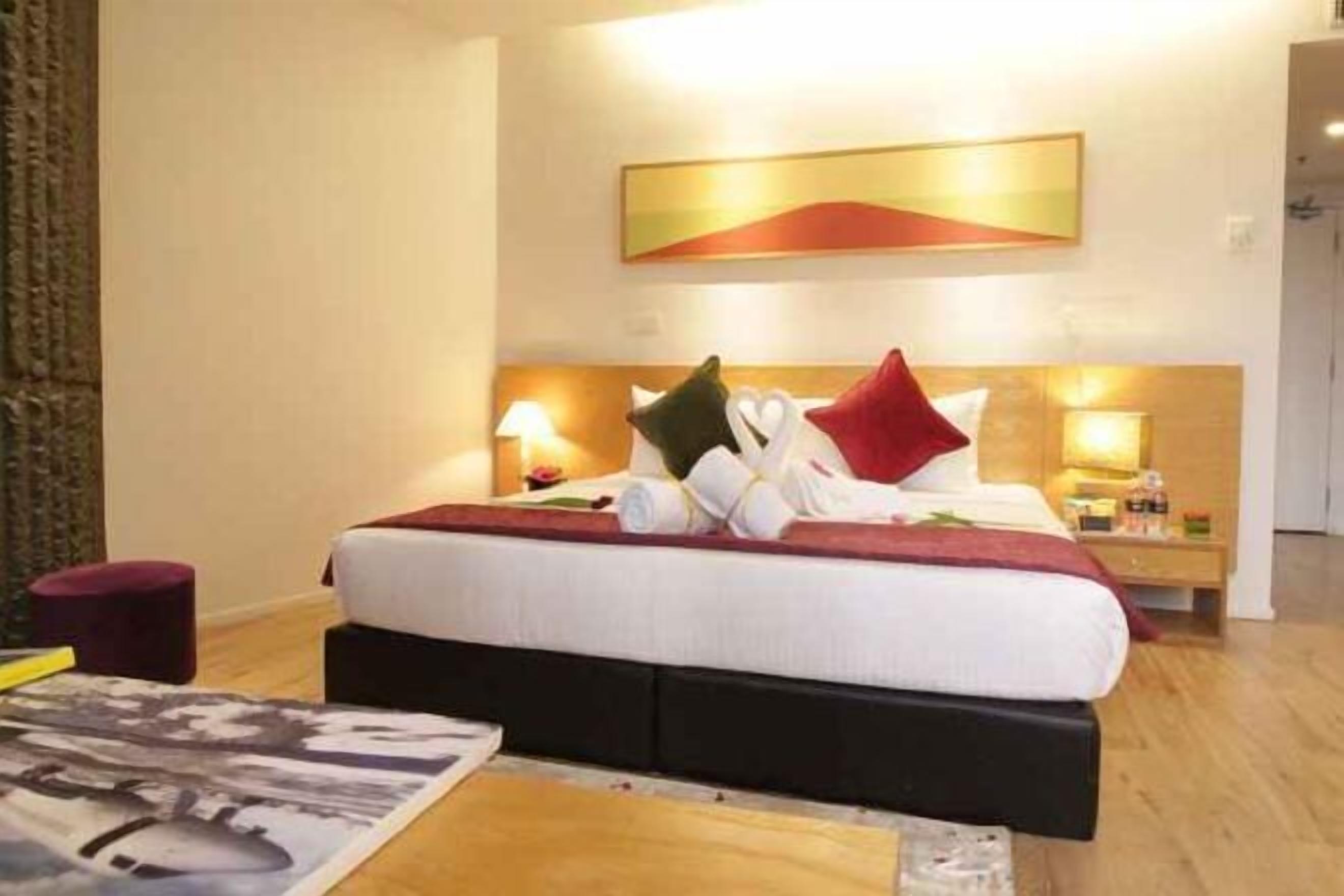 Habitación de hotel con cama, mesitas de noche, un cuadro en la pared y suelo de madera.