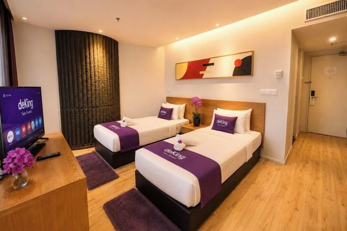 Ein Hotelzimmer mit zwei Betten, einem Schreibtisch mit Computer und einem Fernseher.
