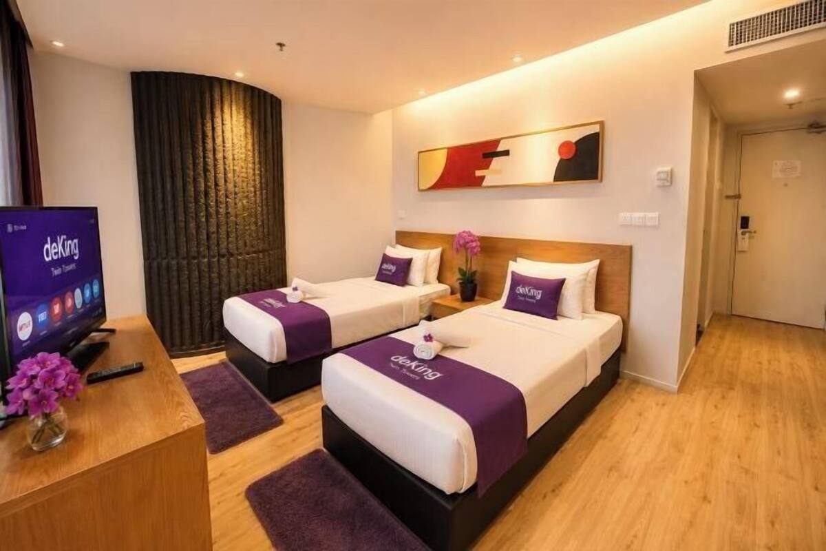 Ein Hotelzimmer mit zwei Betten, einem Schreibtisch mit Computer und einem Fernseher.
