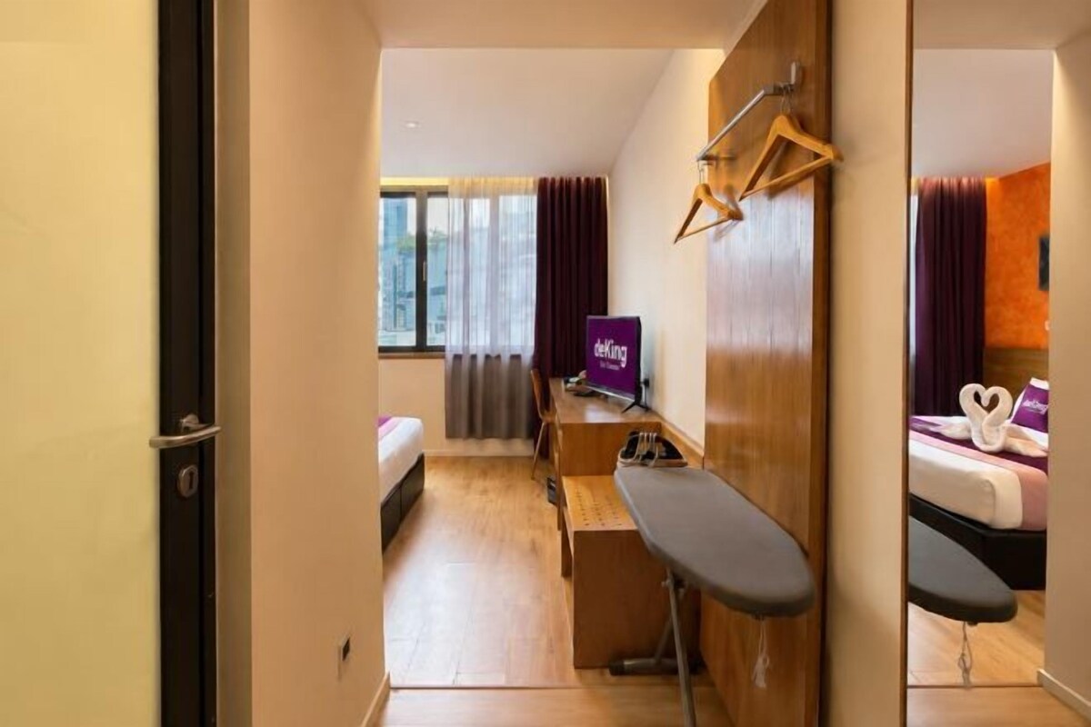 Hotellihuone, jossa on sänky, työpöytä, tuoli ja näkymä kaupunkiin.