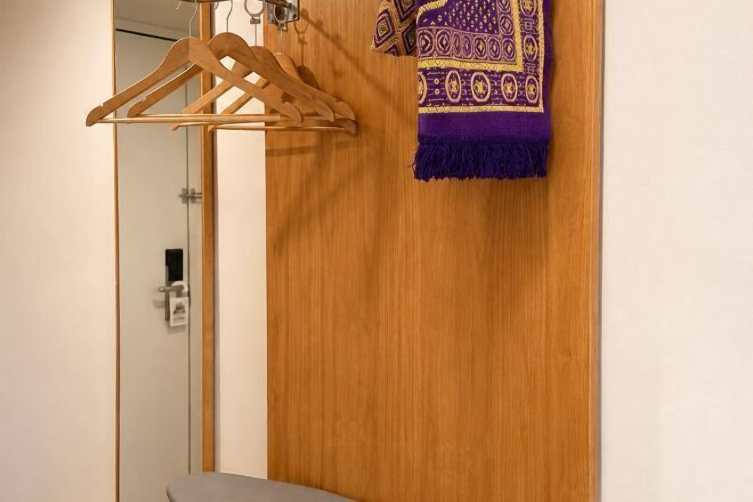 A wooden wardrobe with a purple patterned towel hanging on it.