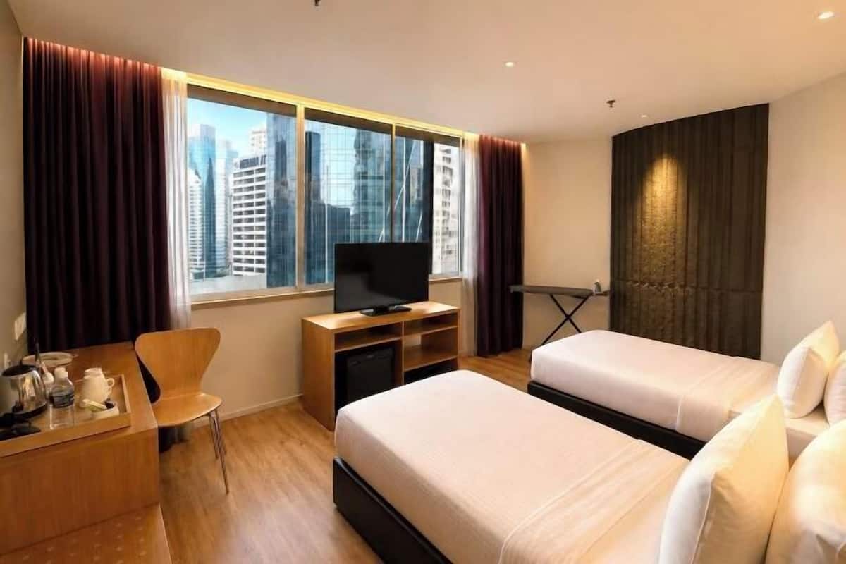 Ein Hotelzimmer mit Bett, Schreibtisch, Stuhl, Fernseher und einem fenster mit Vorhängen.