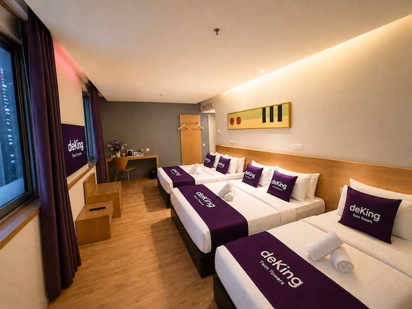 Une chambre d’hôtel avec quatre lits, un bureau, une chaise et une fenêtre avec des rideaux.