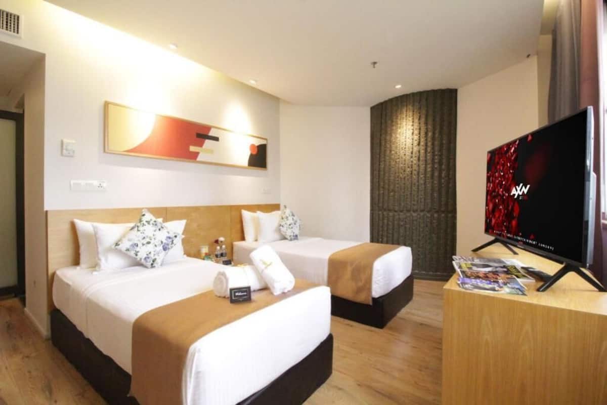 Ein Hotelzimmer mit zwei Betten, einem Fernseher und einem Holztisch.