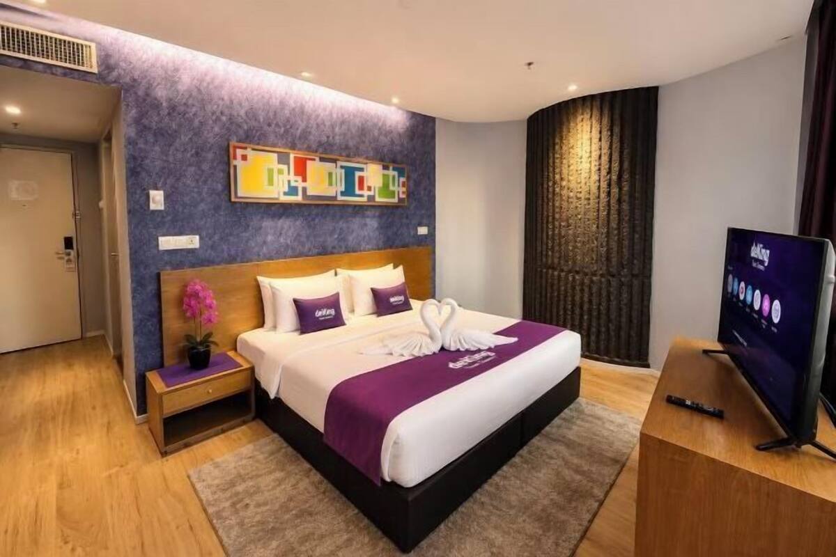 Ein modernes Hotelzimmer mit einem großen Bett, einem Fernseher, einem Nachttisch und einem Wanddekor.