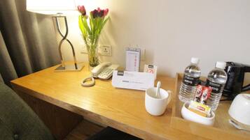 A hotel reception desk with a telephone, a notepad, a mug, and bottled water.