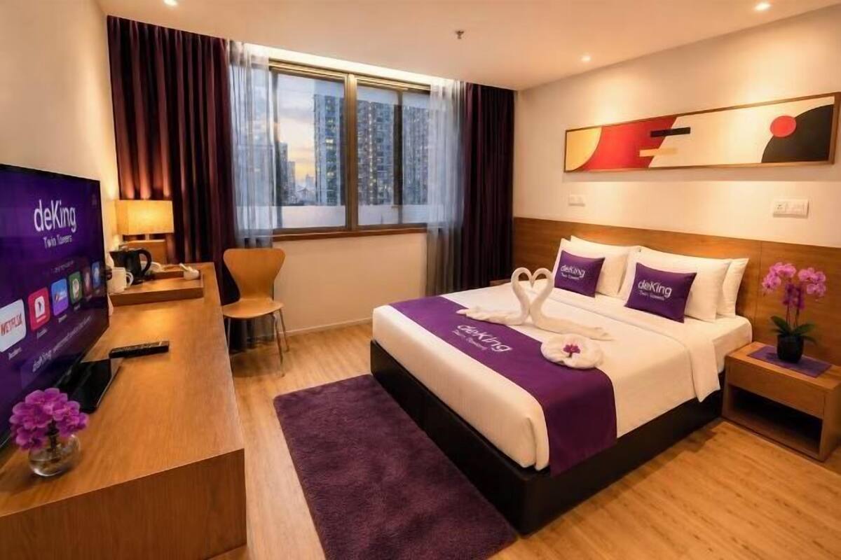 Ein Hotelzimmer mit Bett, Schreibtisch, Fernseher und einem Fenster mit Vorhängen.