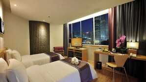 A hotel room with two beds, a desk, a chair, a TV, and a view of a cityscape at night. - de King Hotel Klcc (Kuala Lumpur)