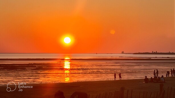 A sunset over a beach with people walking and sitting on the sand. - L'Abri Châtelaillonnais, sleeps 7, close to the beach and market. (Châtelaillon-Plage)