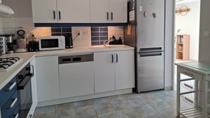 A modern kitchen with white cabinets, a microwave, a coffee maker, and a refrigerator. - L'Abri Châtelaillonnais, sleeps 7, close to the beach and market. (Châtelaillon-Plage)