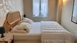 A bedroom with a bed, bedside table, lamp, and window. - L'Abri Châtelaillonnais, sleeps 7, close to the beach and market. (Châtelaillon-Plage)