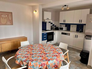 Una cucina compatta con mobili bianchi, un forno a microonde, un tostapane e un fornello.