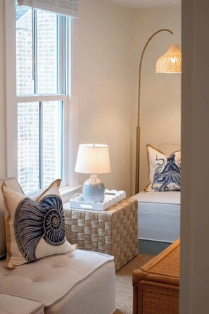 A cozy bedroom with a bed, a bedside lamp, and a window with a view of buildings. - Elegant 2-Bedroom Retreat in Historic Saint Michaels – Walk to Dining & Shops (Saint Michaels)