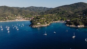 A coastal town with a marina filled with sailboats, surrounded by green hills and clear blue waters. - Villa Mare di Spartaia (Marciana)