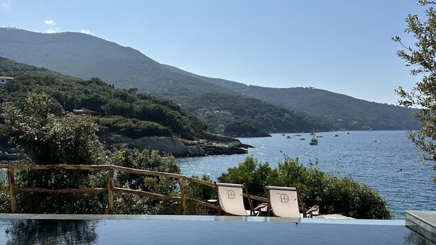 An infinity pool with clear water, wooden deck chairs, and a view of the sea and mountains. - Villa Mare di Spartaia (Marciana)