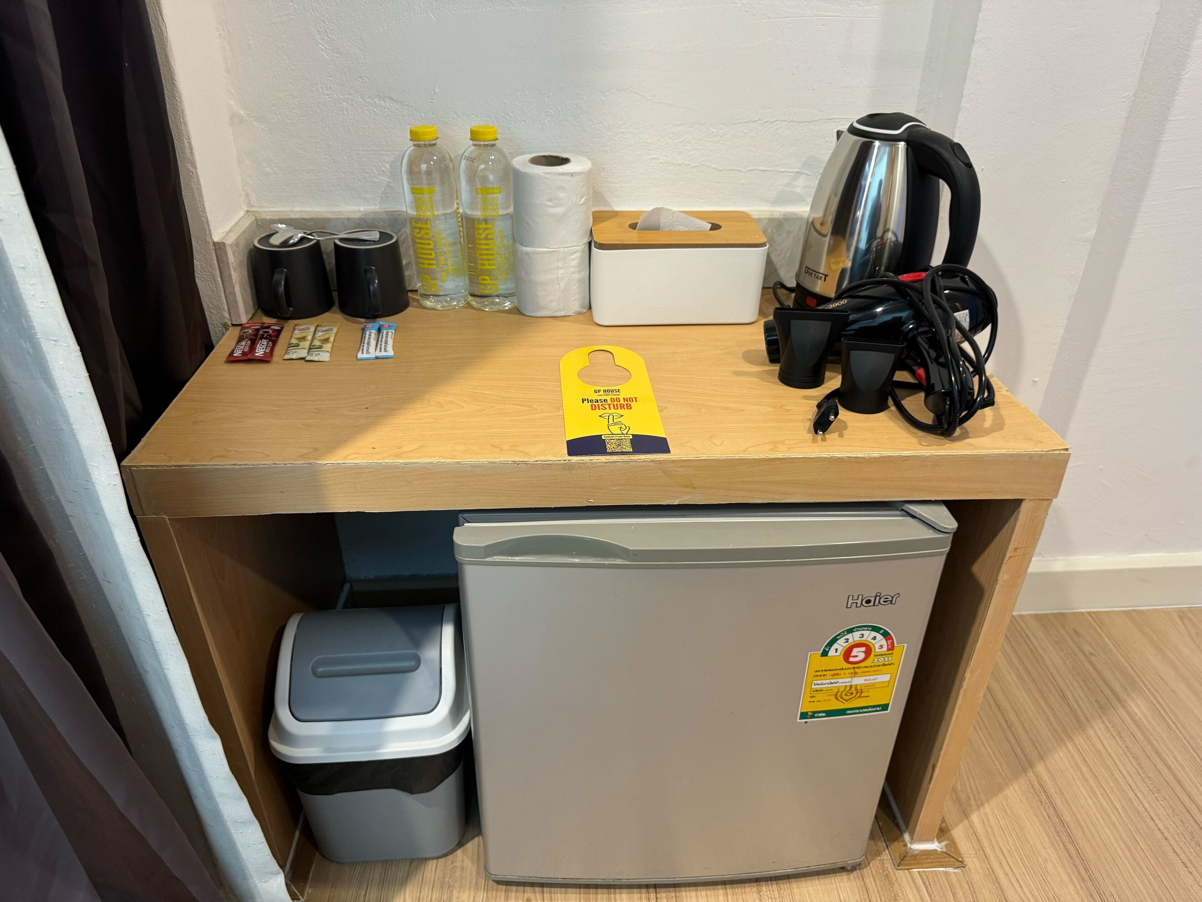 A small kitchenette area with a coffee maker, two bottles of water, a tissue box, and a trash bin.