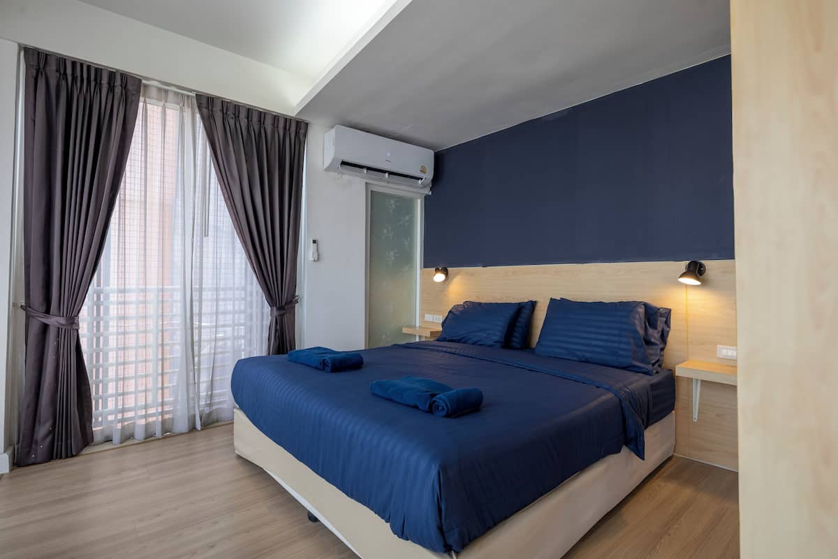 A modern bedroom with a large bed, dark blue bedding, and a ceiling fan.