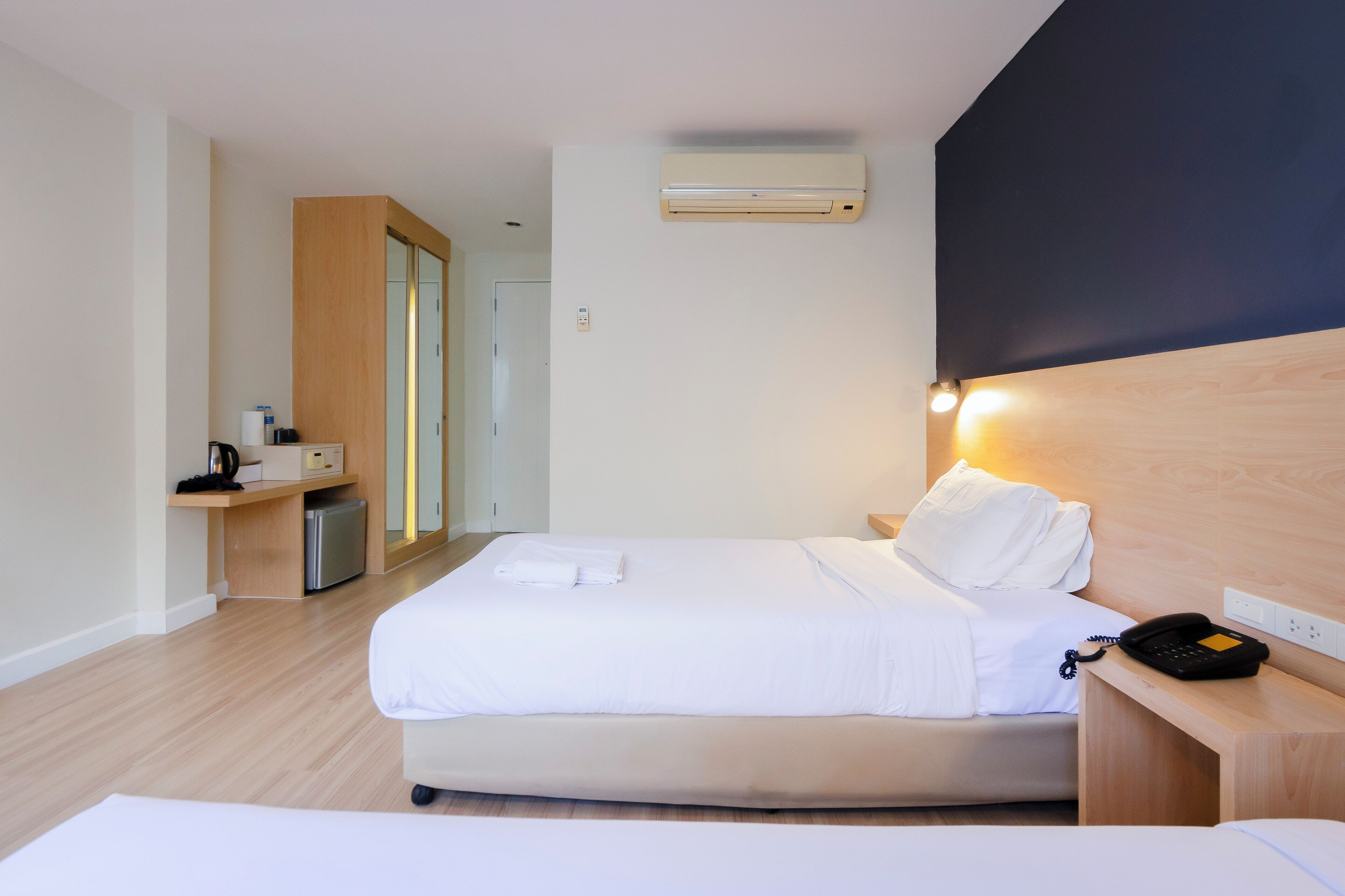 Een hotelkamer met een bed, nachtkastje en een klein bureau met een lamp.