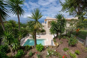A pool surrounded by tropical plants and a house with a tiled roof. - MyExclusiveItaly - Villa with panoramic Vesuvius | Sorrento views & Private Pool (Sorrento)