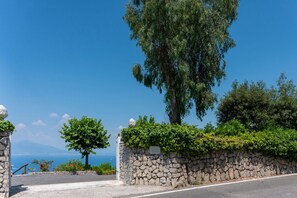 Un muro de piedra con una puerta, un árbol y vistas al mar.