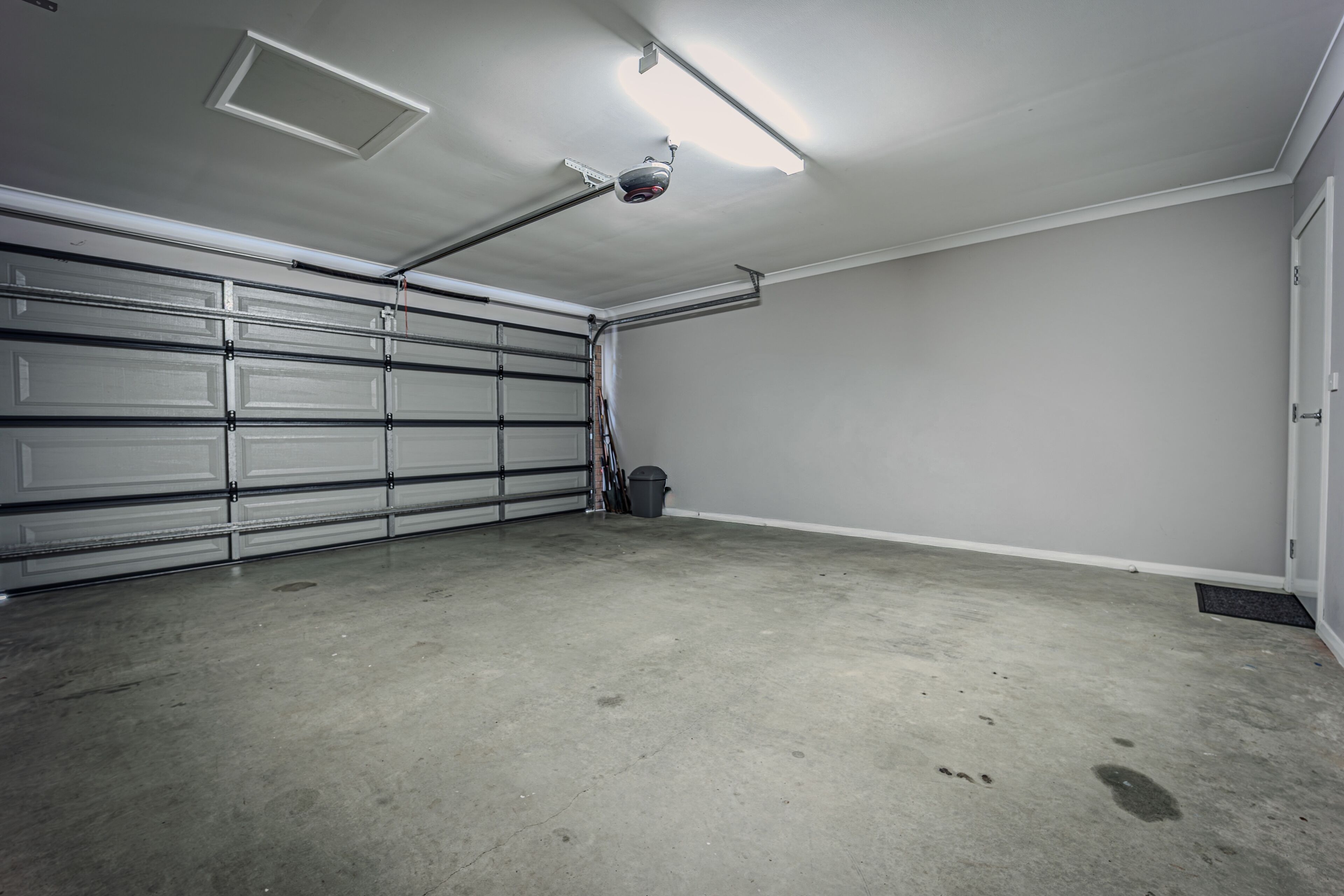 Eine Garage mit Betonboden, einer weißen Tür und einer Deckenleuchte.