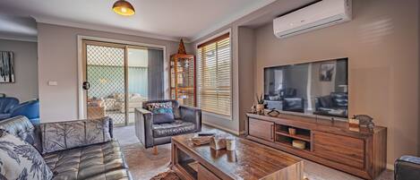 A modern living room with a leather sofa, a wooden coffee table, and a TV on a wooden cabinet.