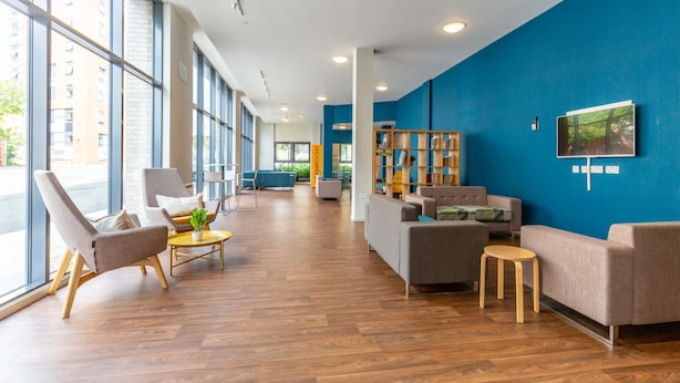 A spacious lobby with a blue accent wall, wooden flooring, and modern furniture including sofas and armchairs. - For Students Only Bryson Court (Newcastle-upon-Tyne)