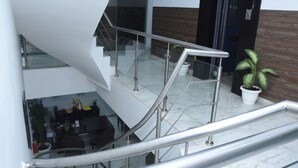 Een modern interieur met een glazen wenteltrap, een zithoek met tafels en stoelen, en een potplant.