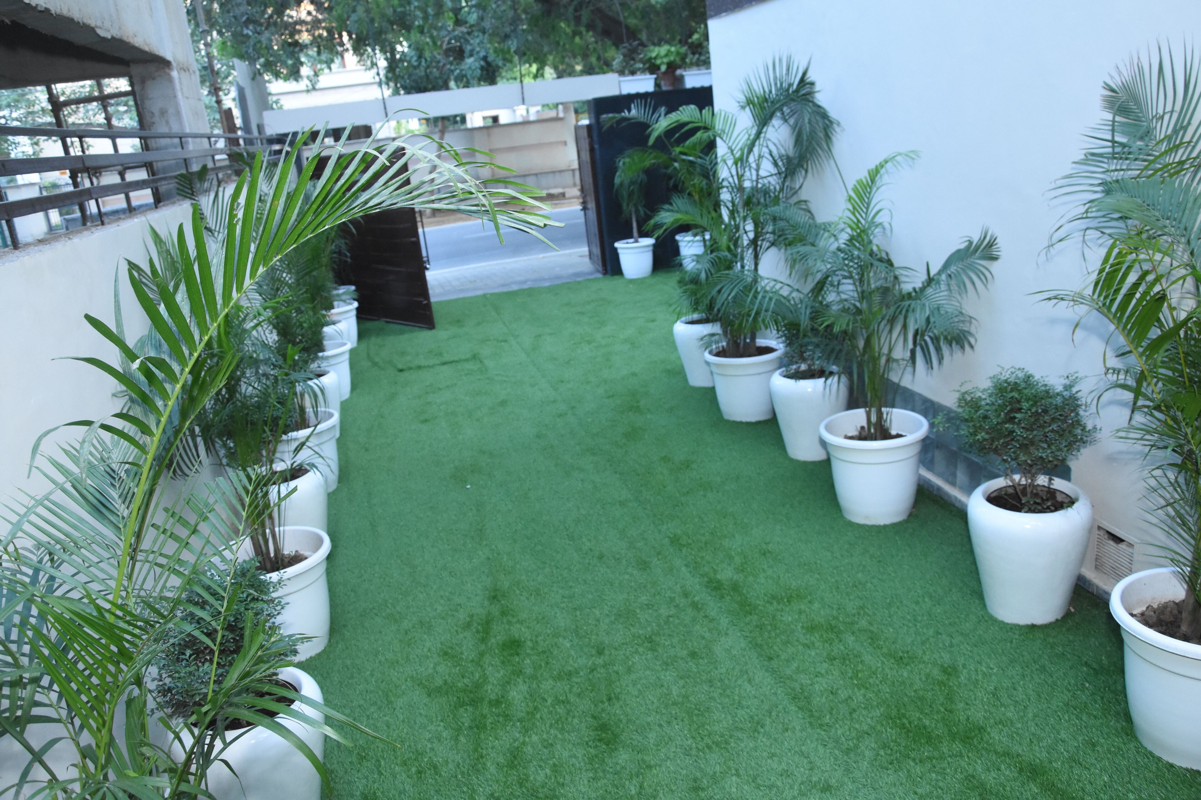 A courtyard with artificial green turf and potted plants.